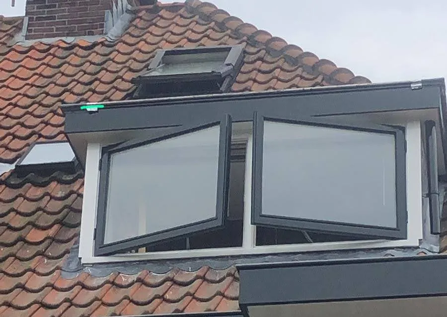 Afgewerkte dakkapel met antracietgrijze betimmering en witte kozijnen tussen rode dakpannen
