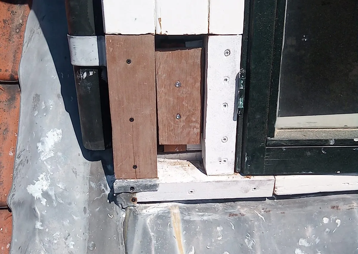 Nieuw hout ingelaten in de hoek van een dakkapel en vastgezet met schroeven, klaar om te worden gegrond